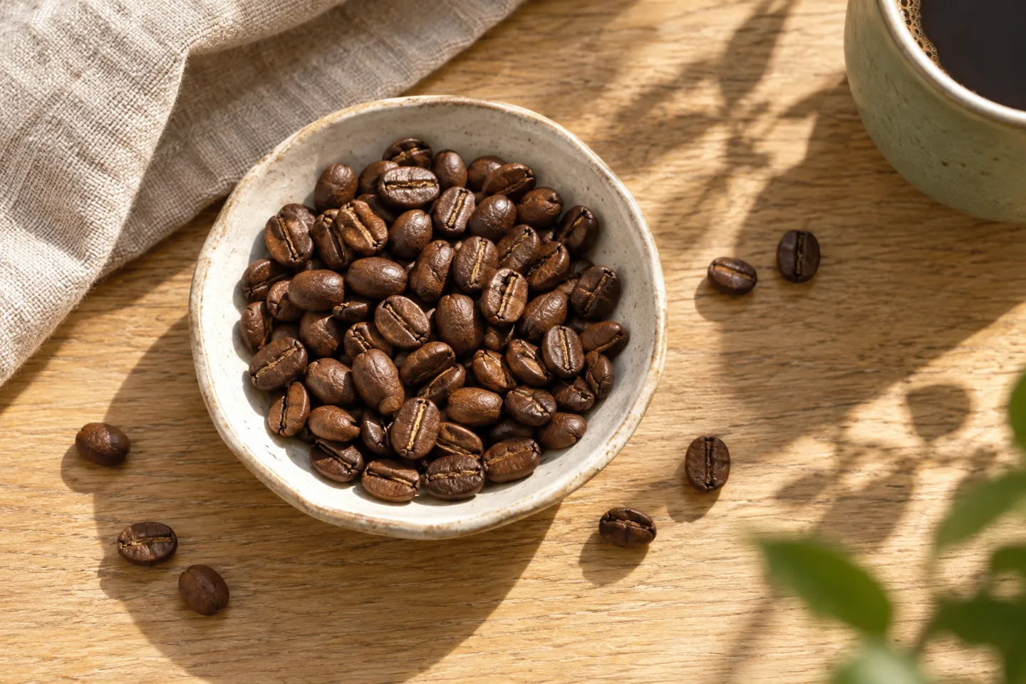 Roasted coffee beans in a handmade ceramic bowl on an oak table